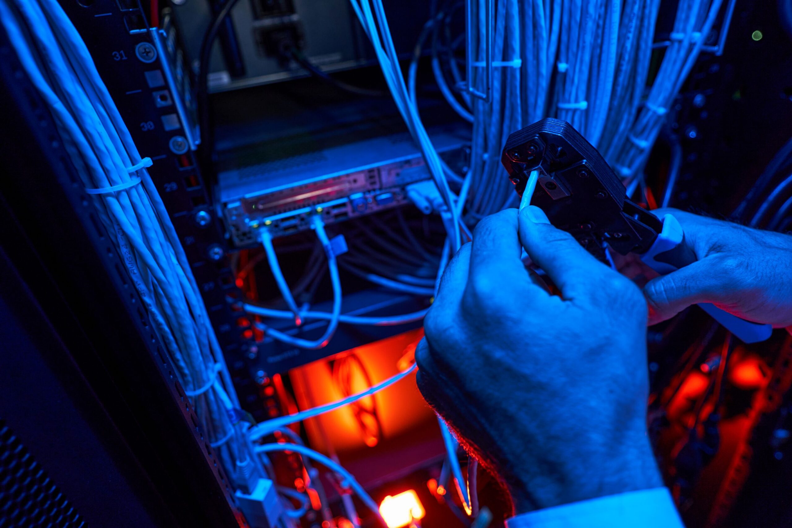 Technician installing data and communications cabling with crimping tool in server rack – Illawarra & Shoalhaven cabling services